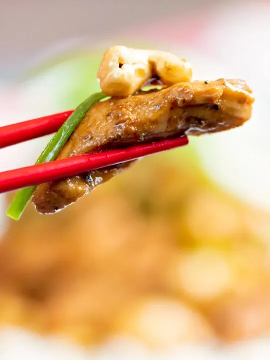 Close up Szechuan chicken with being held with chopsticks.