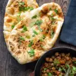 Overhead tandoori naan bread with coriander served with chole.
