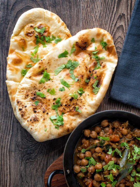 Overhead tandoori naan bread with coriander served with chole.