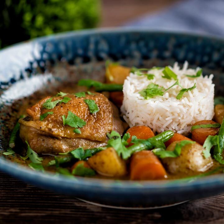 Vietnamese chicken curry or ca ri ga with rice and vegetables in a deep blue bowl.