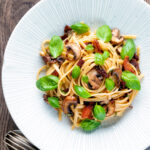 Overhead bacon and mushroom pasta with sun dried tomatoes.