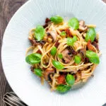 Overhead bacon and mushroom pasta with sun dried tomatoes.