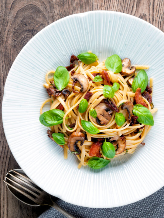 Overhead bacon and mushroom pasta with sun dried tomatoes.