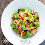 Overhead bacon and mushroom pasta with sun dried tomatoes featuring a title overlay.