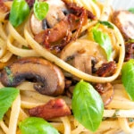 Close up bacon and mushroom pasta with sun dried tomatoes.