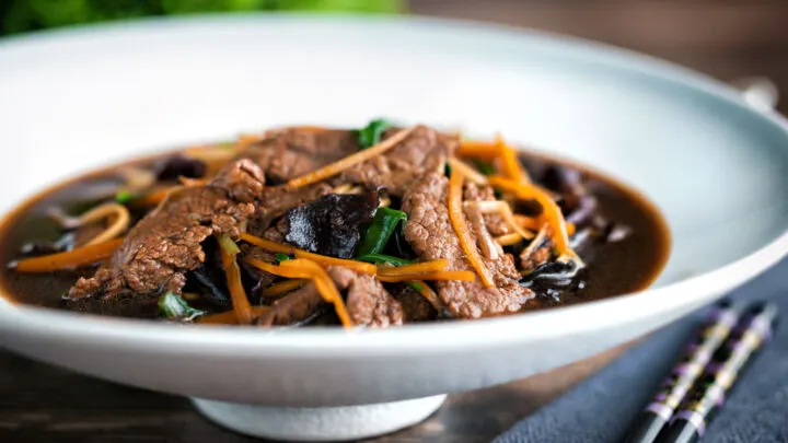 Beef noodle soup featuring spinach & dried mushrooms in a dark soy broth.