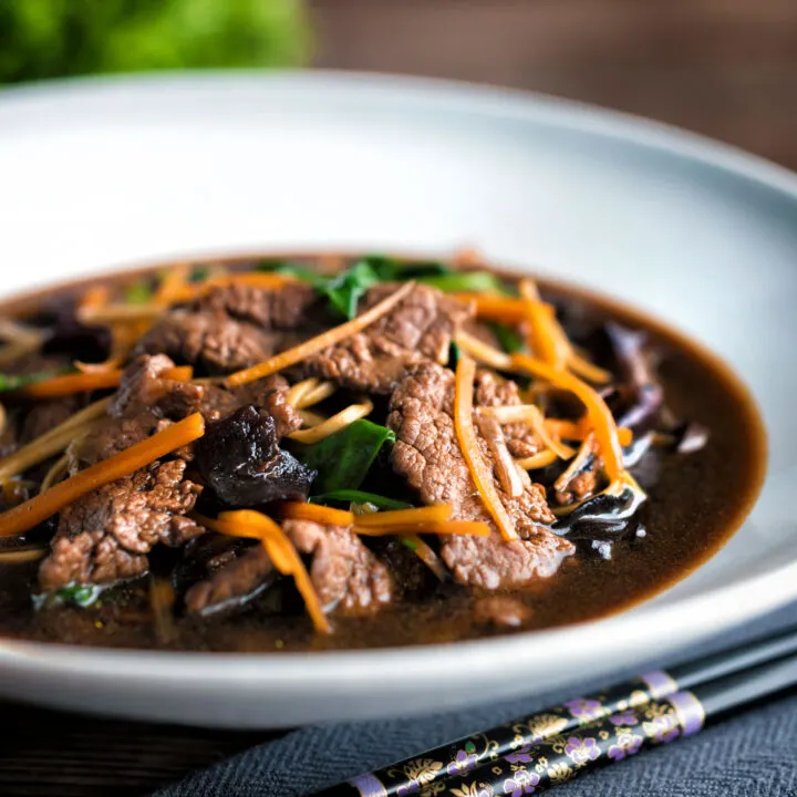 Beef noodle soup featuring spinach & dried mushrooms in a dark soy broth.