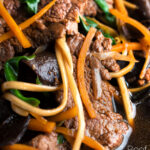 beef noodle soup featuring udon noodles & spinach in a dark soy broth featuring a title overlay.