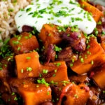 Close up butternut squash chilli served with brown rice, and sour cream featuring a title overlay.