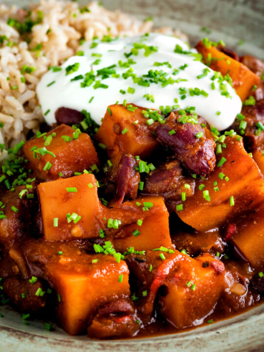 Close up butternut squash chilli served with brown rice, and sour cream.