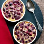 Overhead individual cherry clafoutis desserts served in brul&eacute;e pots.