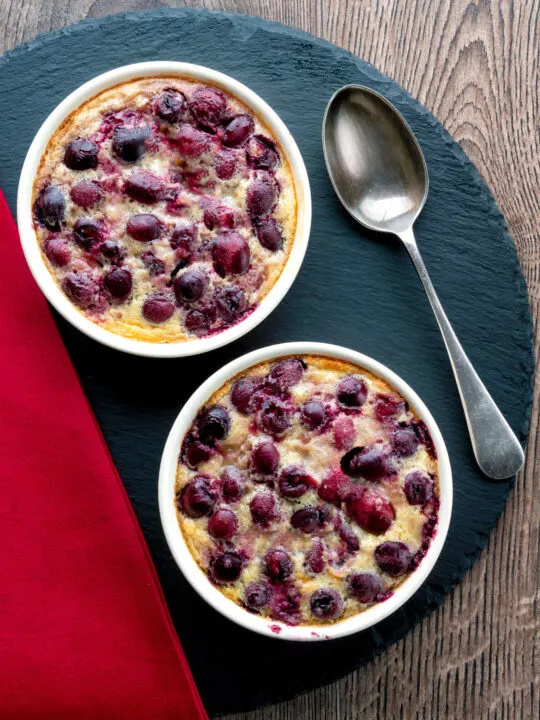 Overhead individual cherry clafoutis desserts served in brulée pots.