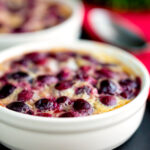 Individual cherry clafoutis desserts served in brulée pots featuring a title overlay.