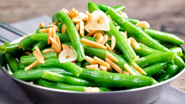 Garlic green beans served in a small pan garnished with almonds.