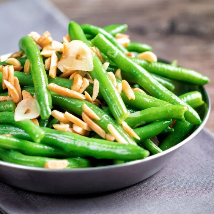 Garlic green beans served in a small pan garnished with almonds.