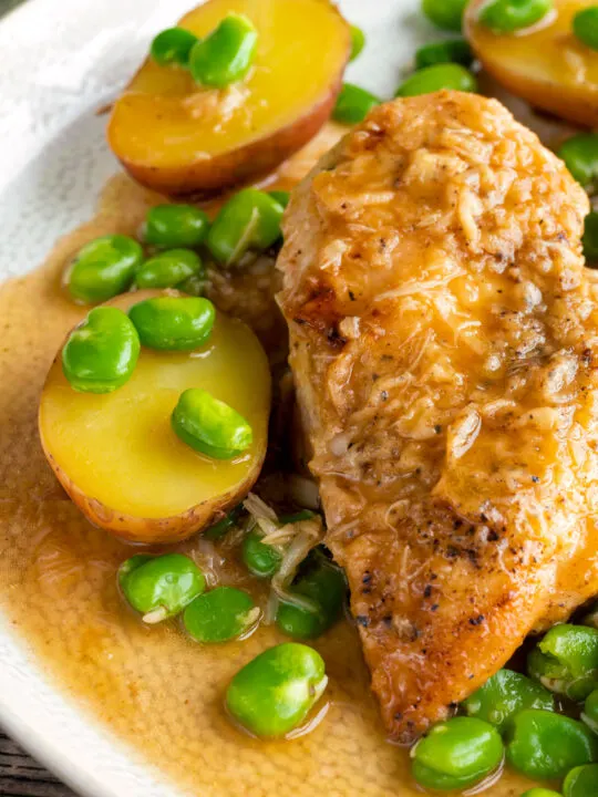 Close up garlic lemon chicken breast served with potatoes and broad beans