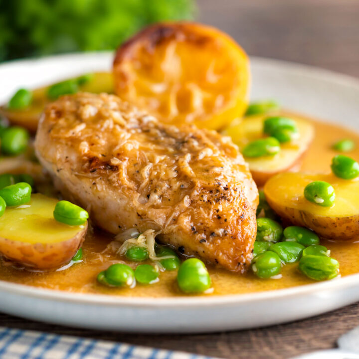 Garlic lemon chicken breast served with potatoes and broad beans in a sauce.