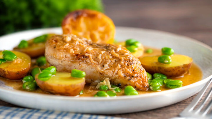 Garlic lemon chicken breast served with potatoes and broad beans in a sauce.
