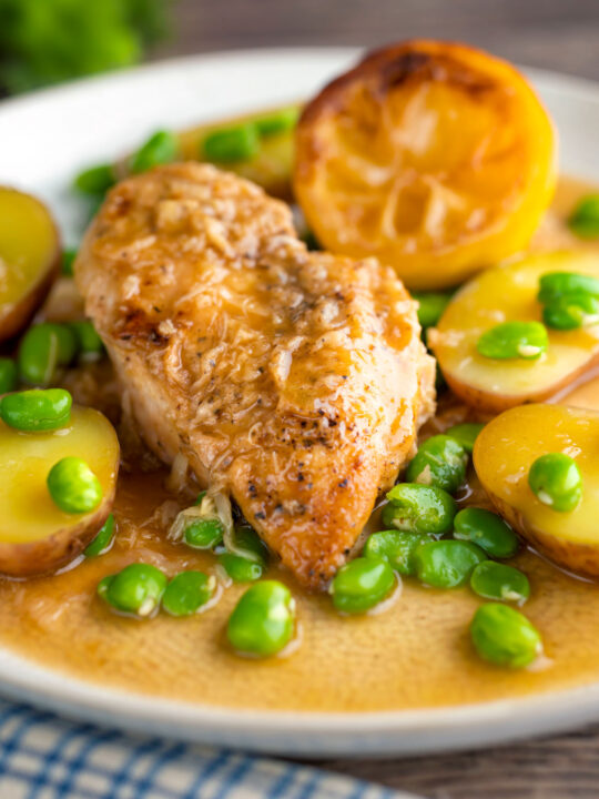 Garlic lemon chicken breast served with potatoes and broad beans.