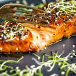 Honey soy salmon served on a black plate showing internal texture.