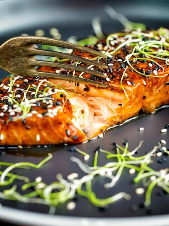 Honey soy salmon served on a black plate showing internal texture.