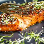 Honey soy salmon served on a black plate showing internal texture featuring a title overlay.