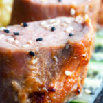 Close up honey and miso glazed pork tenderloin with sesame seeds.
