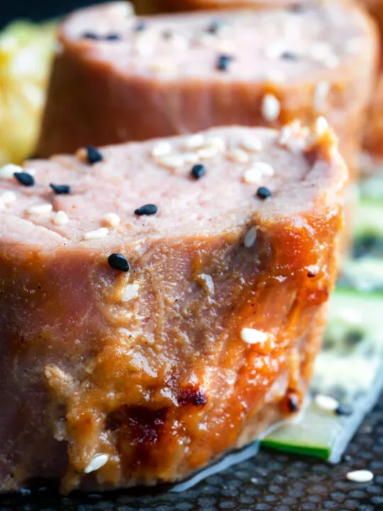 Close up honey and miso glazed pork tenderloin with sesame seeds.