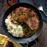 Overhead image of an Indian duck breast curry served with rice and naan bread.