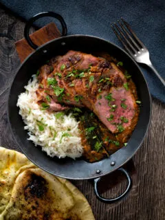 Overhead image of an Indian duck breast curry served with rice and naan bread.