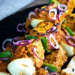 Close up lamb tikka kebabs with onion and green pepper.