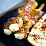 Lamb tikka kebabs with onion and green pepper served with a naan bread.