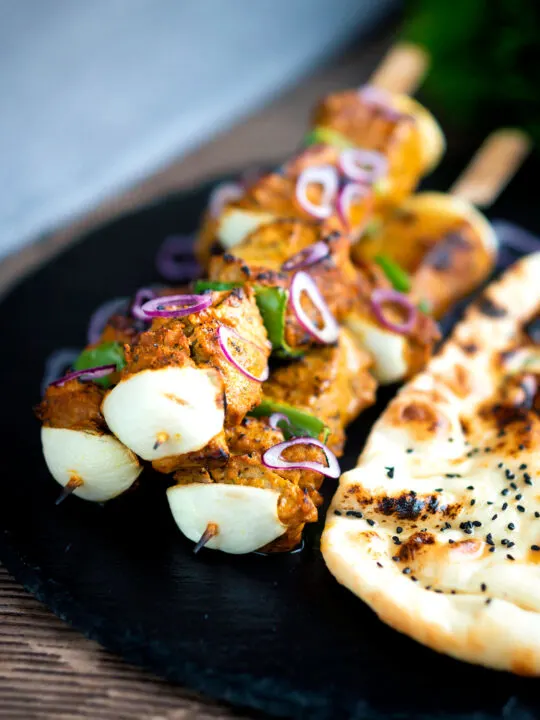 Lamb tikka kebabs with onion and green pepper served with a naan bread.