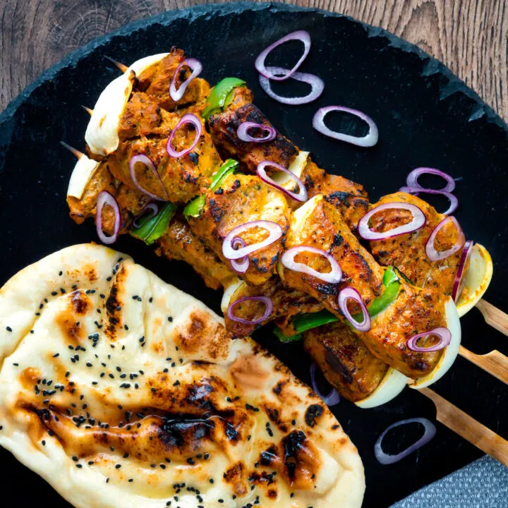 Lamb tikka kebabs with onion and green pepper served with a naan bread and red onion.