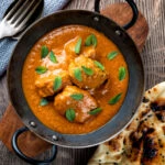 Overhead Indian lamb tikka masala curry served with a naan bread.