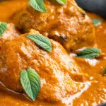 Close up Indian lamb tikka masala curry served peppermint leaves.