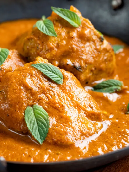 Close up Indian lamb tikka masala curry served peppermint leaves.