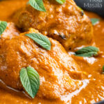 Close up Indian lamb tikka masala curry served peppermint leaves featuring a title overlay.