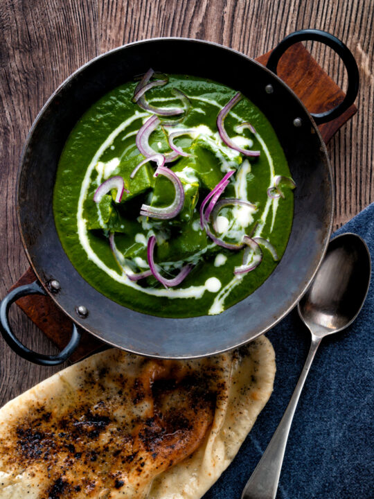 Overhead Indian Palak paneer spinach curry served with naan bread.