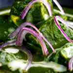Close up Indian palak paneer spinach curry served with naan bread featuring a title overlay.