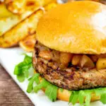 Pork and apple burgers served with rocket, chutney and a side of potato wedges.
