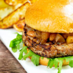 Pork and apple burgers served with rocket, chutney and a side of potato wedges featuring a title overlay.