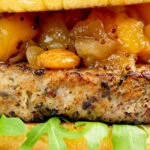 Closeup pork and apple burgers served with rocket, chutney.