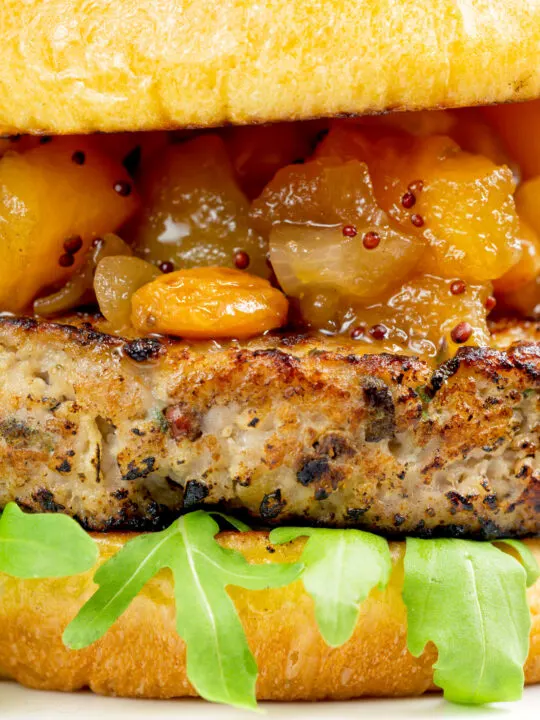 Closeup pork and apple burgers served with rocket, chutney.