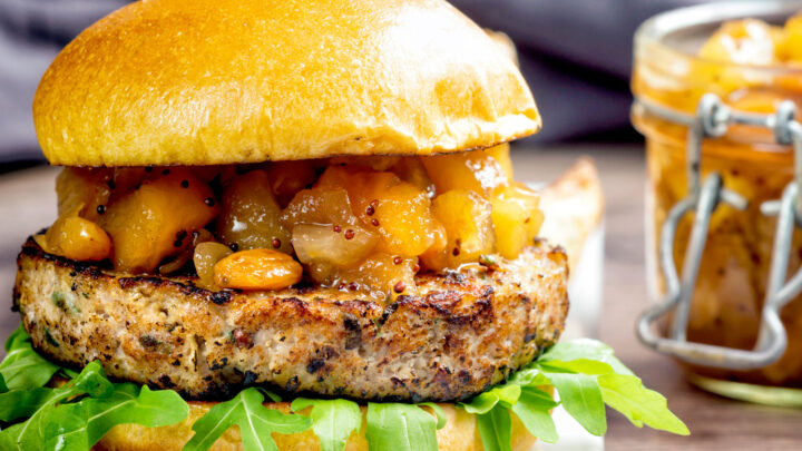 Close up pork and apple burgers served with rocket and apple chutney served on a bun.