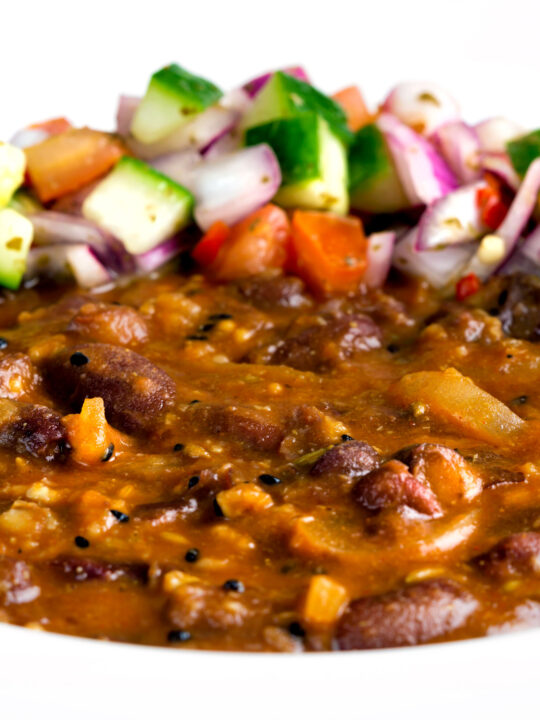 Close up rajma masala kidney bean curry served with kachumber salad.