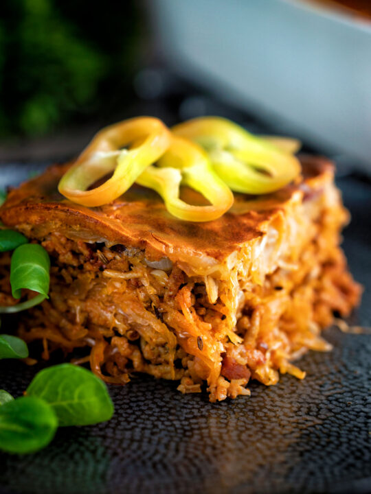 Rakott kaposzta, Hungarian sauerkraut casserole served on a black plate.