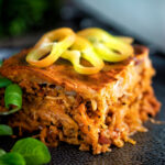 Rakott kaposzta, Hungarian sauerkraut casserole served on a black plate featuring a title overlay.