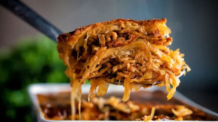 Close up baked rakott kaposzta, Hungarian sauerkraut casserole spooned from a casserole dish.