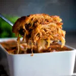 Steaming hot rakott kaposzta, Hungarian sauerkraut casserole being removed from a bowl.